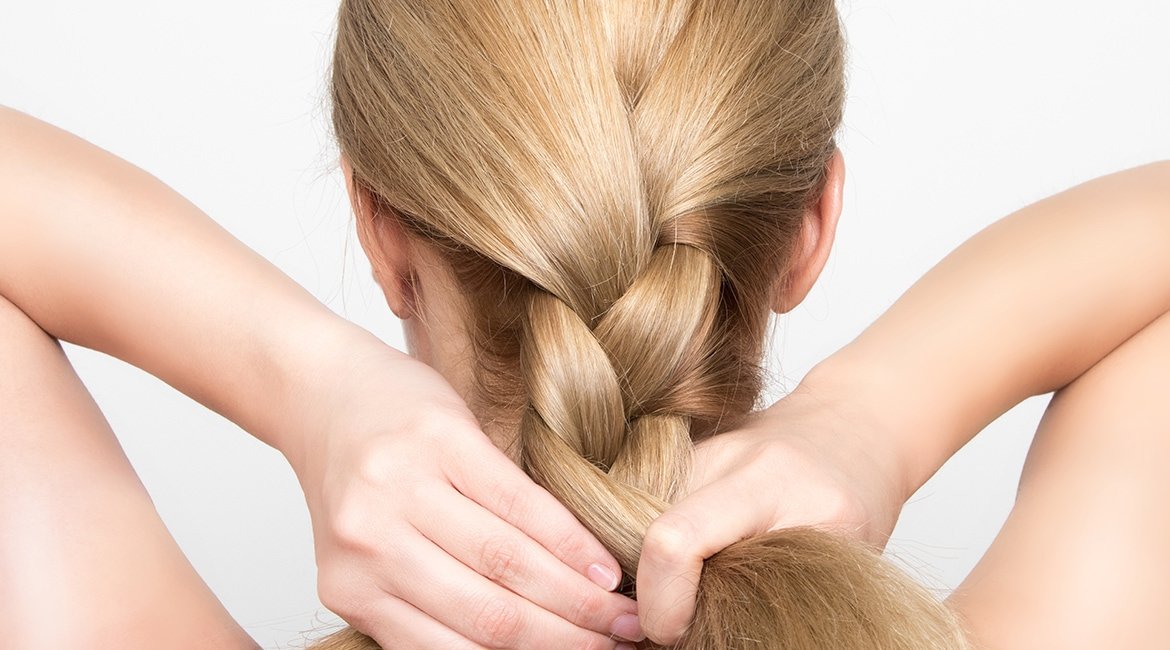 Frau mit blonden Haaren richtet ihren geflochtenen Zopf